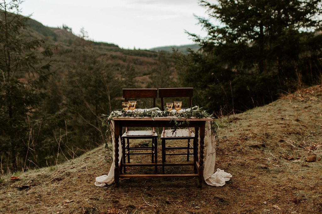 Boho intimate wedding sweetheart table on a cliffside with a valley behind.