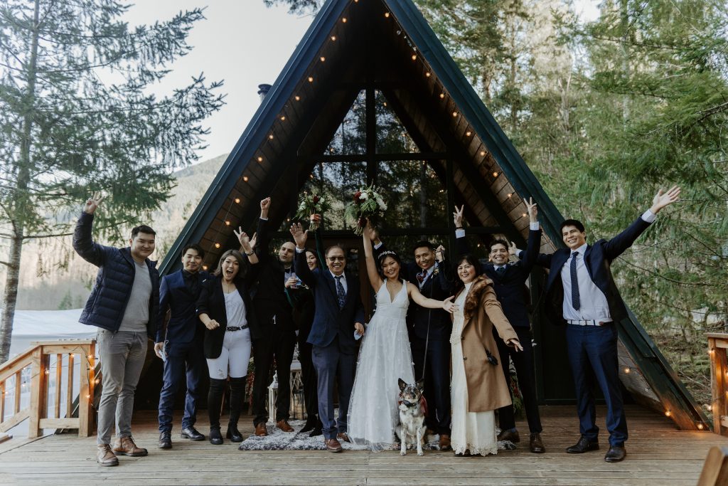 Bride and groom posing with their family at an A-frame cabin for their elopement ceremony.