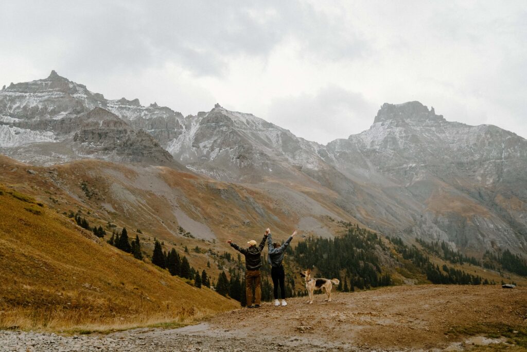 Couple facing away from the camera towards the mountains in southern Colorado with a german shepherd dog. 