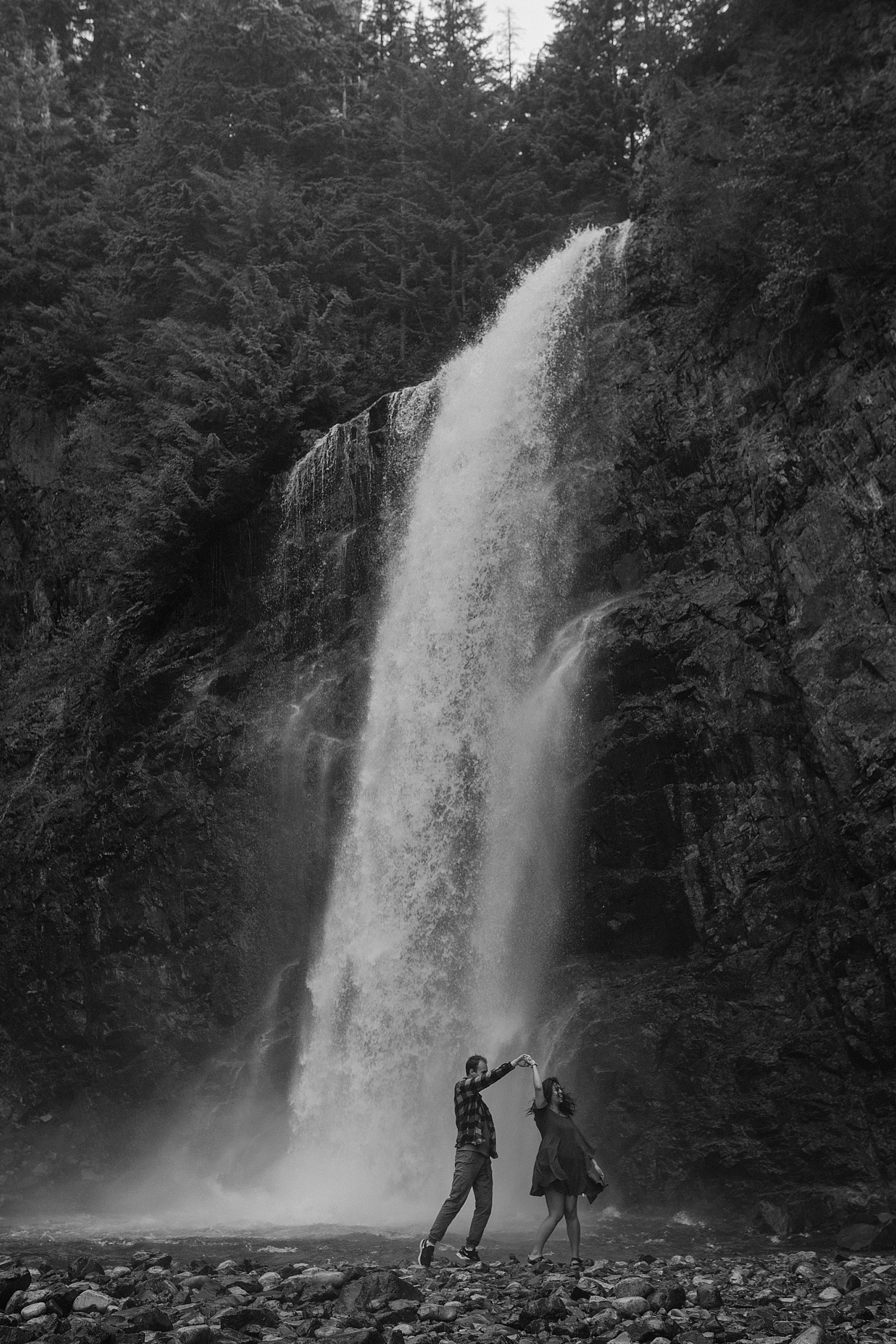 Black and white photo of a couple kissing under a waterfall