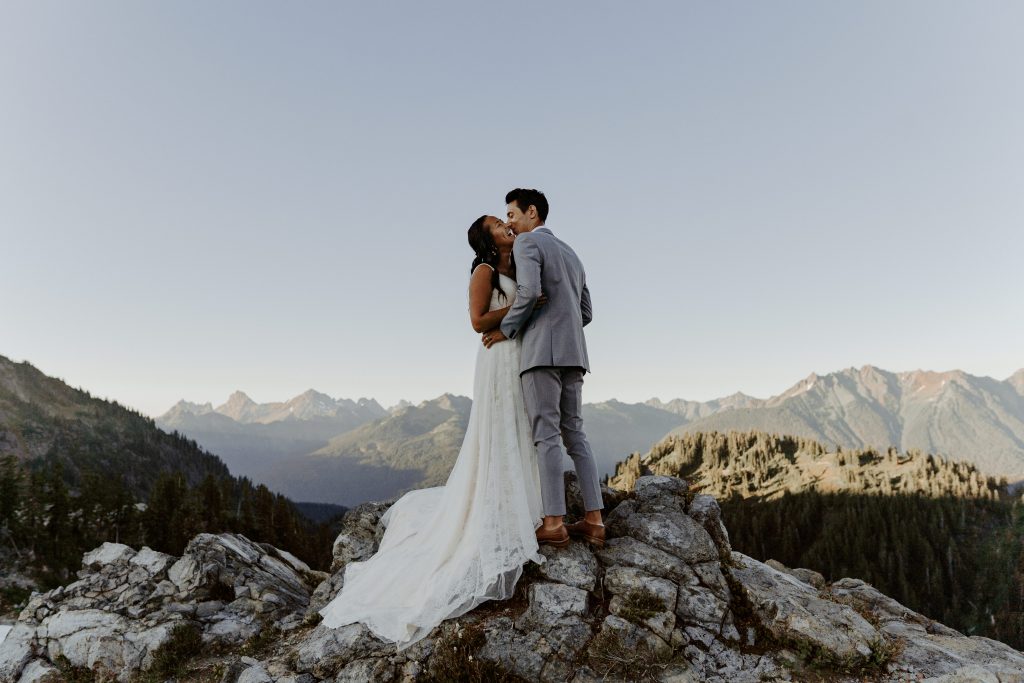 Eloping couple kissing with mountains in the background