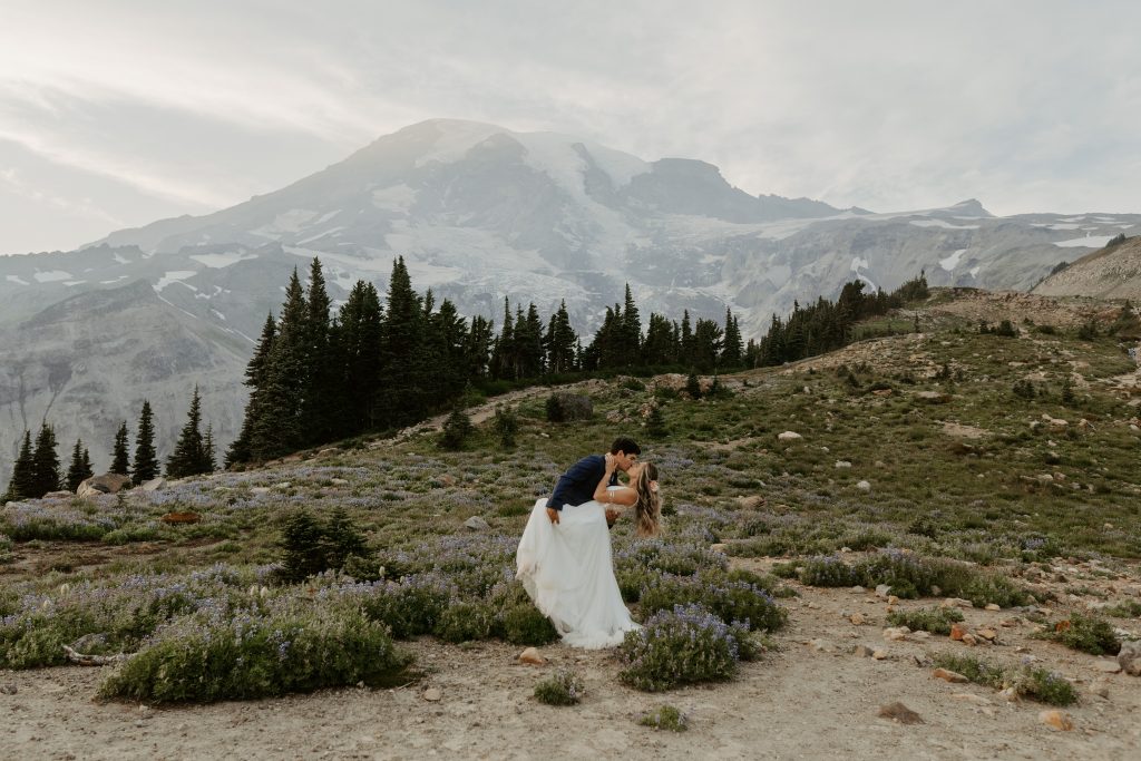 Eloping couple dip kissing with Mount Rainier in the background at sunset 
