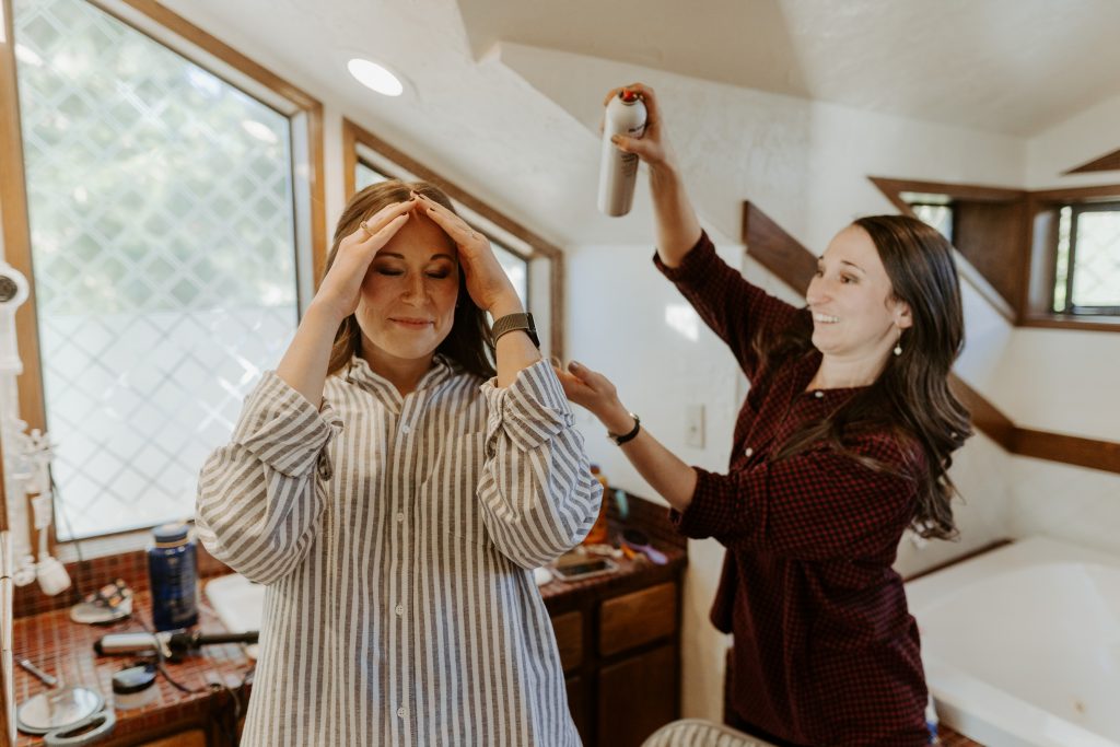 Bride getting her hair done by her sister before the wedding in an Airbnb bathroom. 