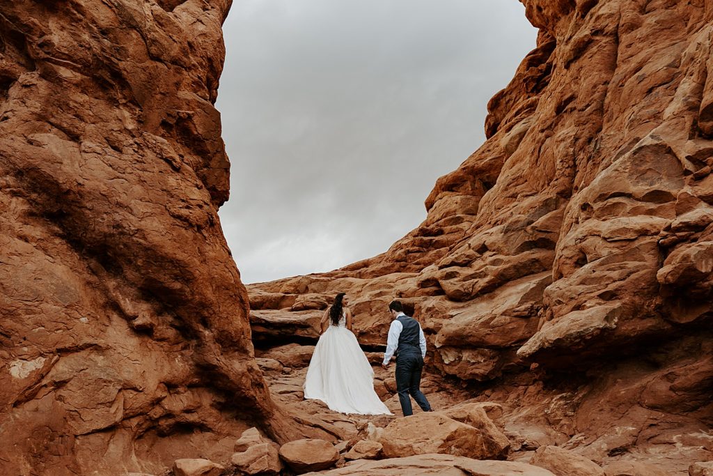 Married couple walking under an arch in Arches National Park Utah