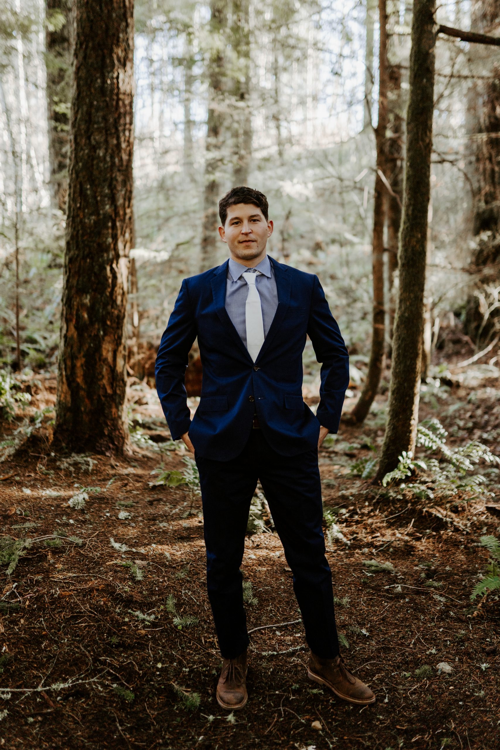 Groom with a navy suit standing in the forest