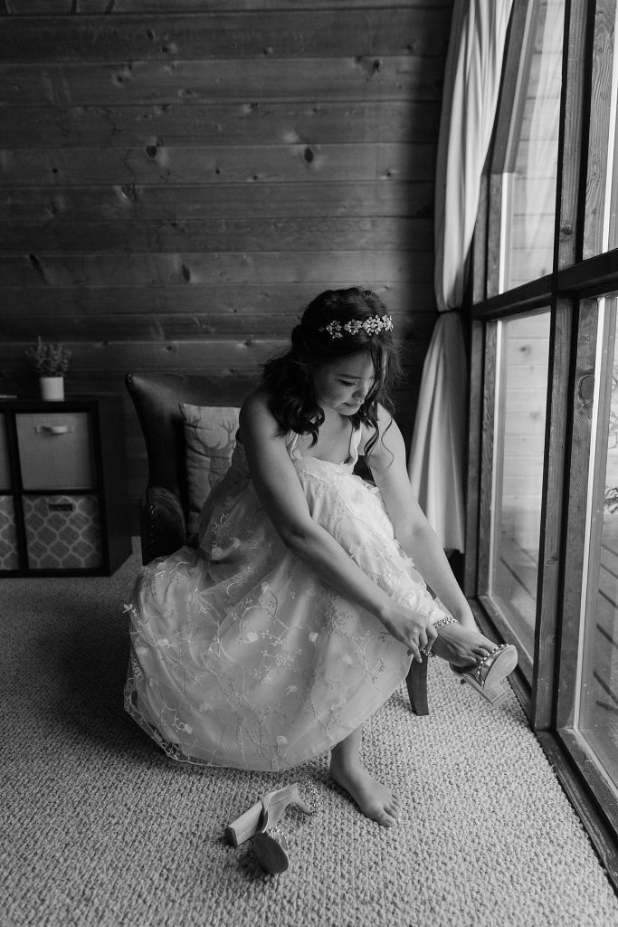 black and white image of a bride putting on her shoes