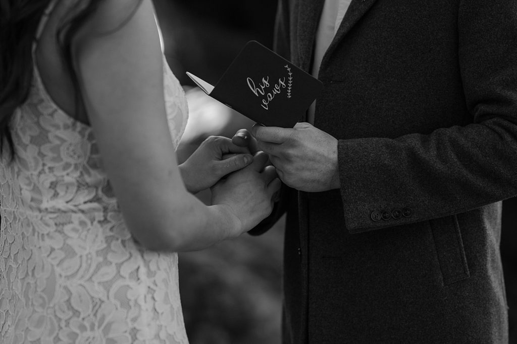 black and white image of a couple holding hands and saying vows