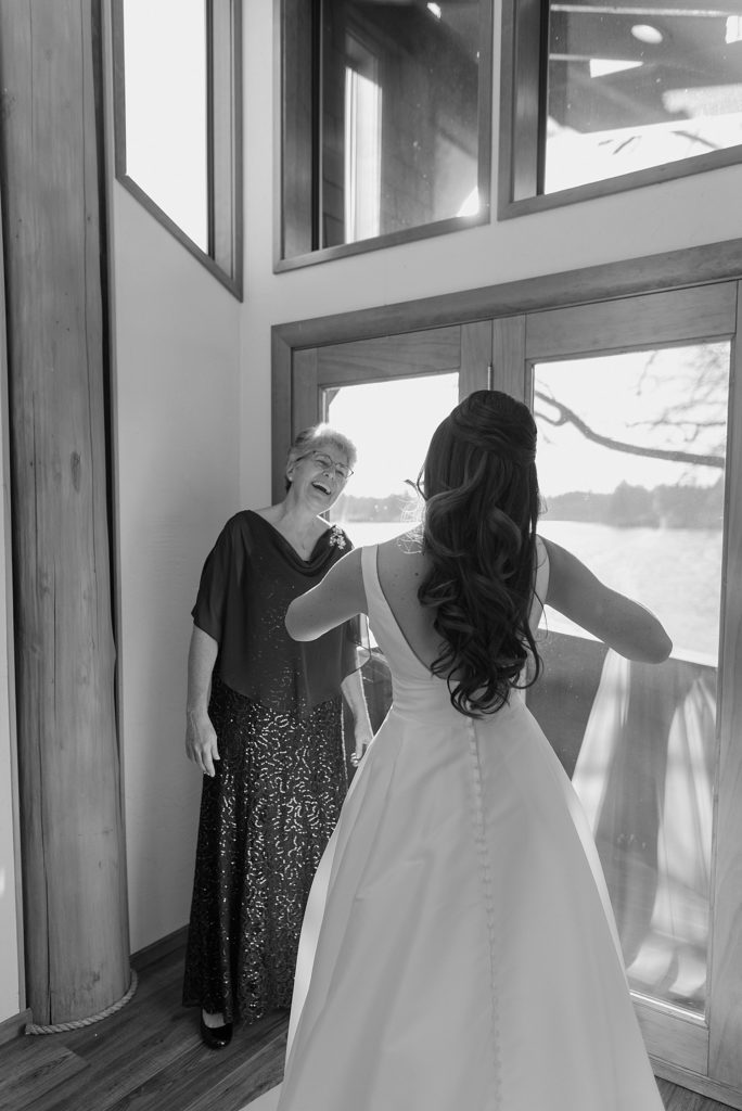 Black and white image of a bride getting her ballgown dress on