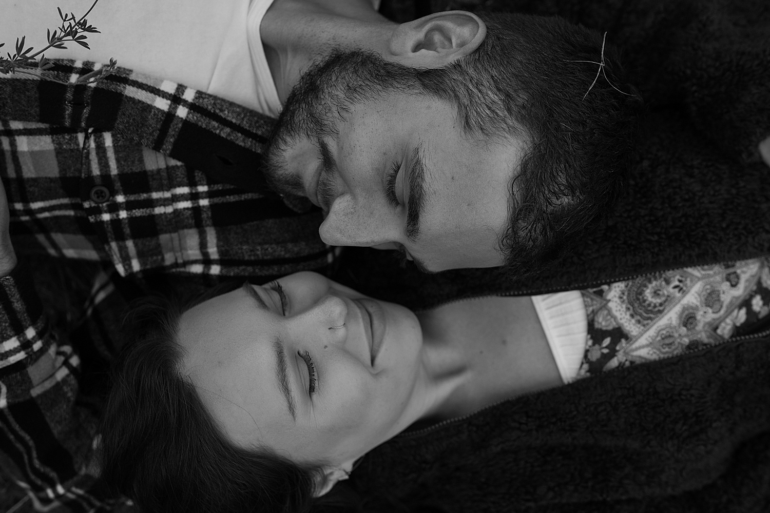 Black and white photo of a couple laying on the ground with their eyes closed