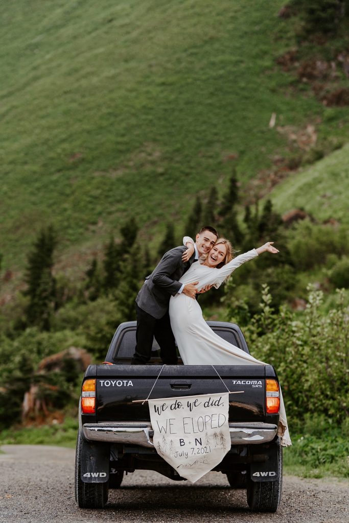 couple standing in the bed of the truck with a "we eloped" sign