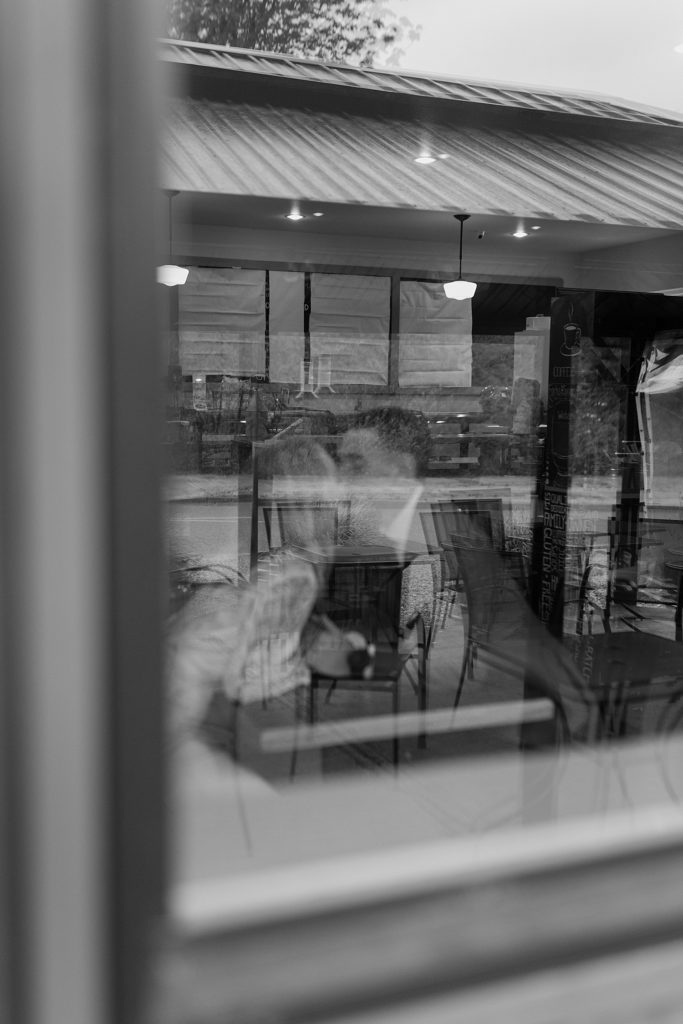 couple kissing behind the window of a bakery