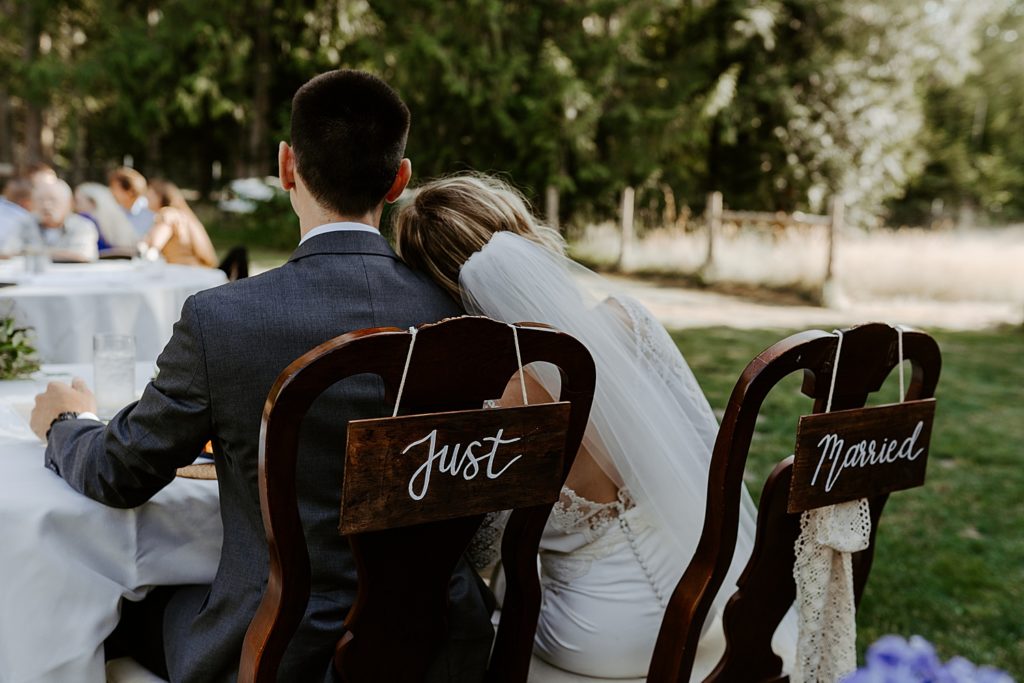 couple sitting at their sweetheart table with a "just married" sign