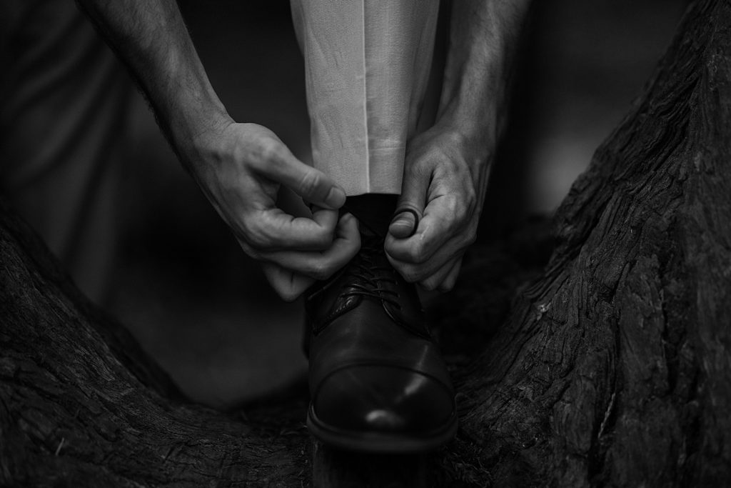 Groom tying his shoess on a Redwoods tree