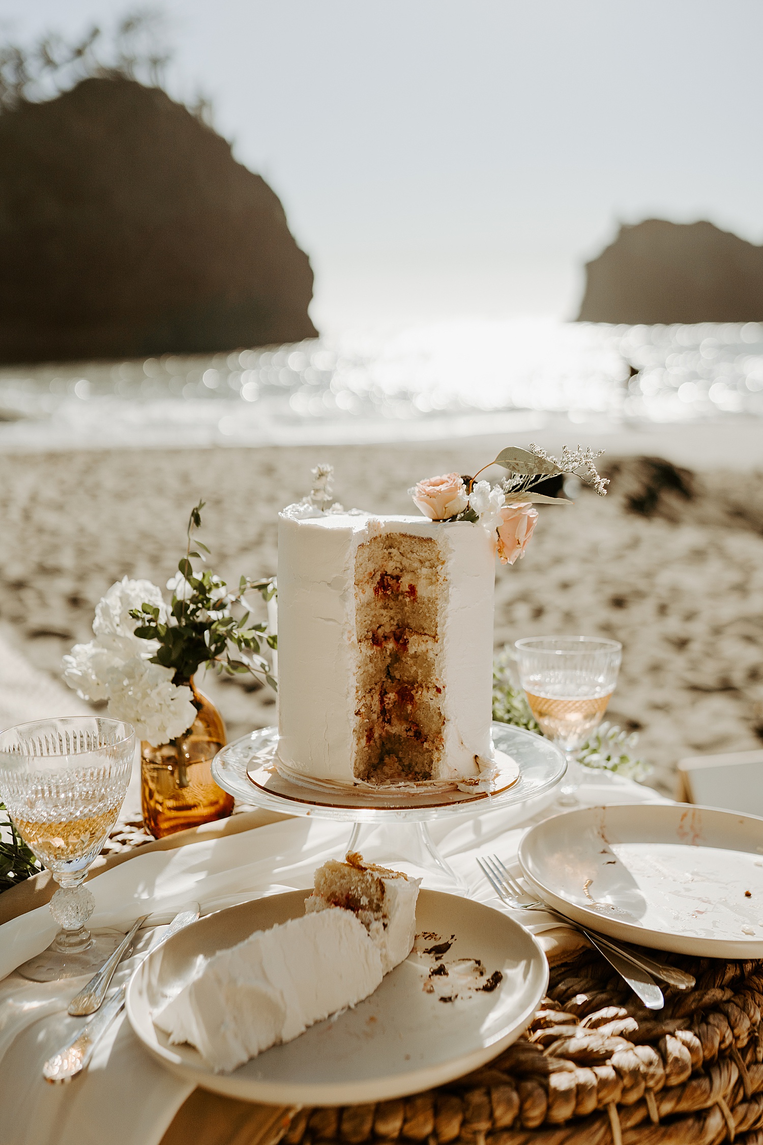 Beach elopement with a white wedding cake and floral details