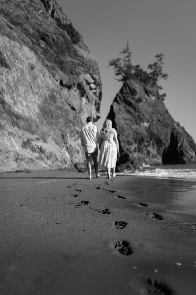 Black and white image of a couple walking along the coast