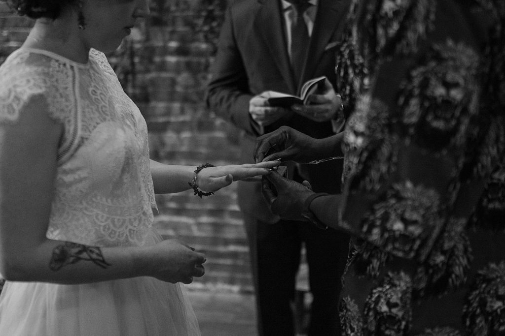 black and white image of groom putting a ring on the bride's finger