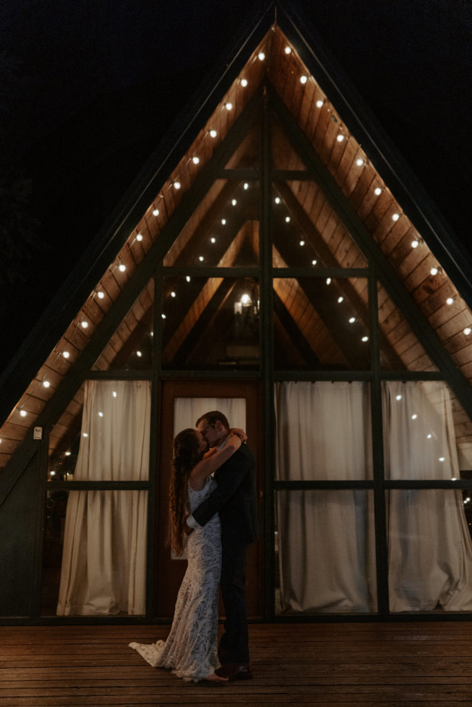 Out of State Elopement Planning Blog - A-frame cabin with a newly married couple kissing