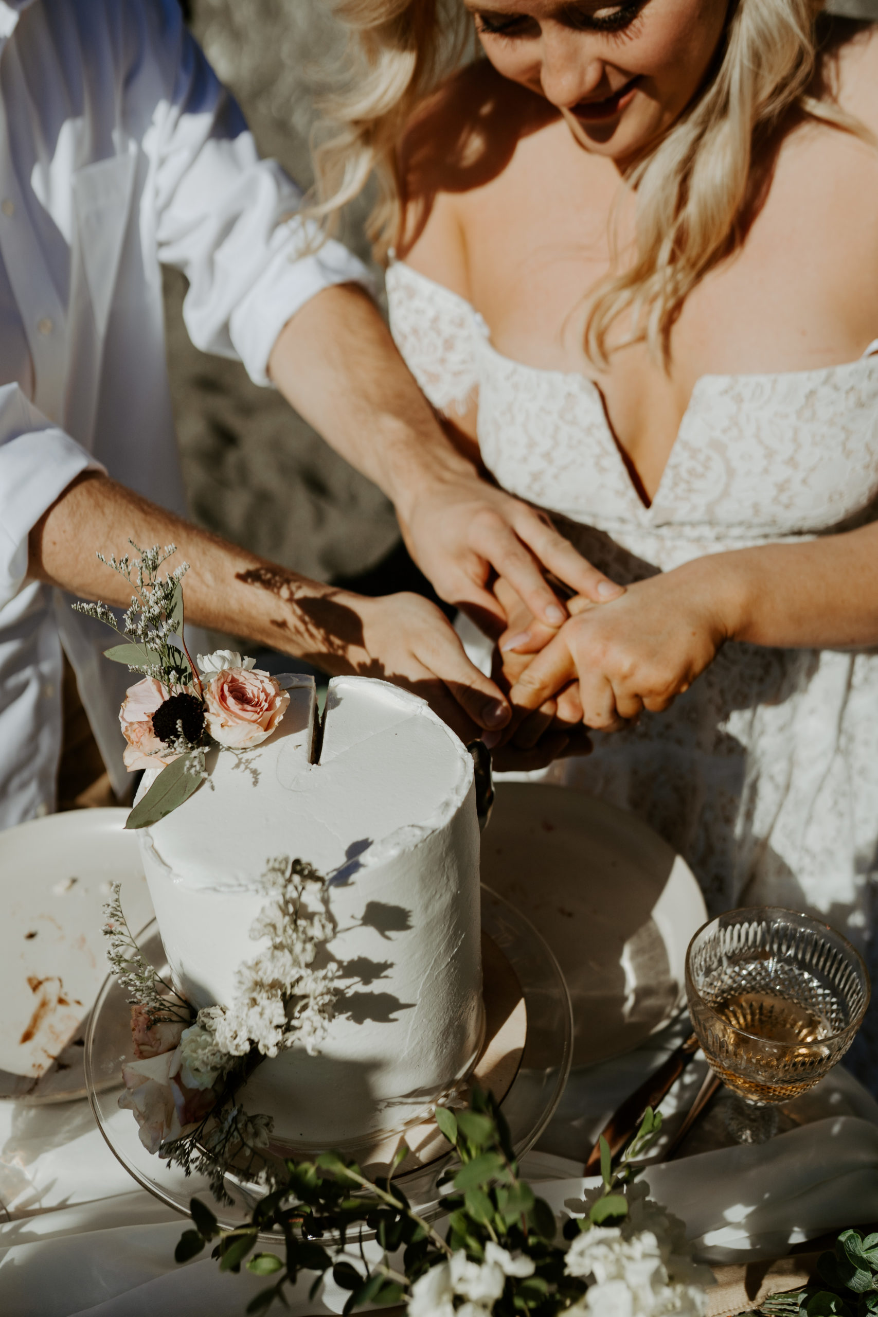 eloping couple cutting their cake at a beach picnic