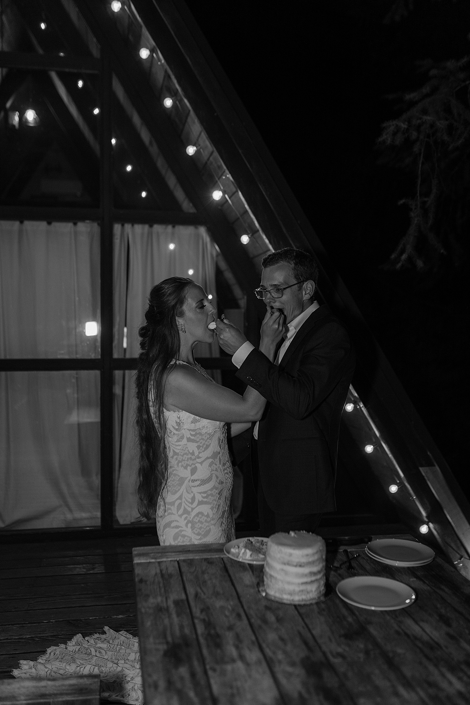 black and white photo of bride and groom sharing cake