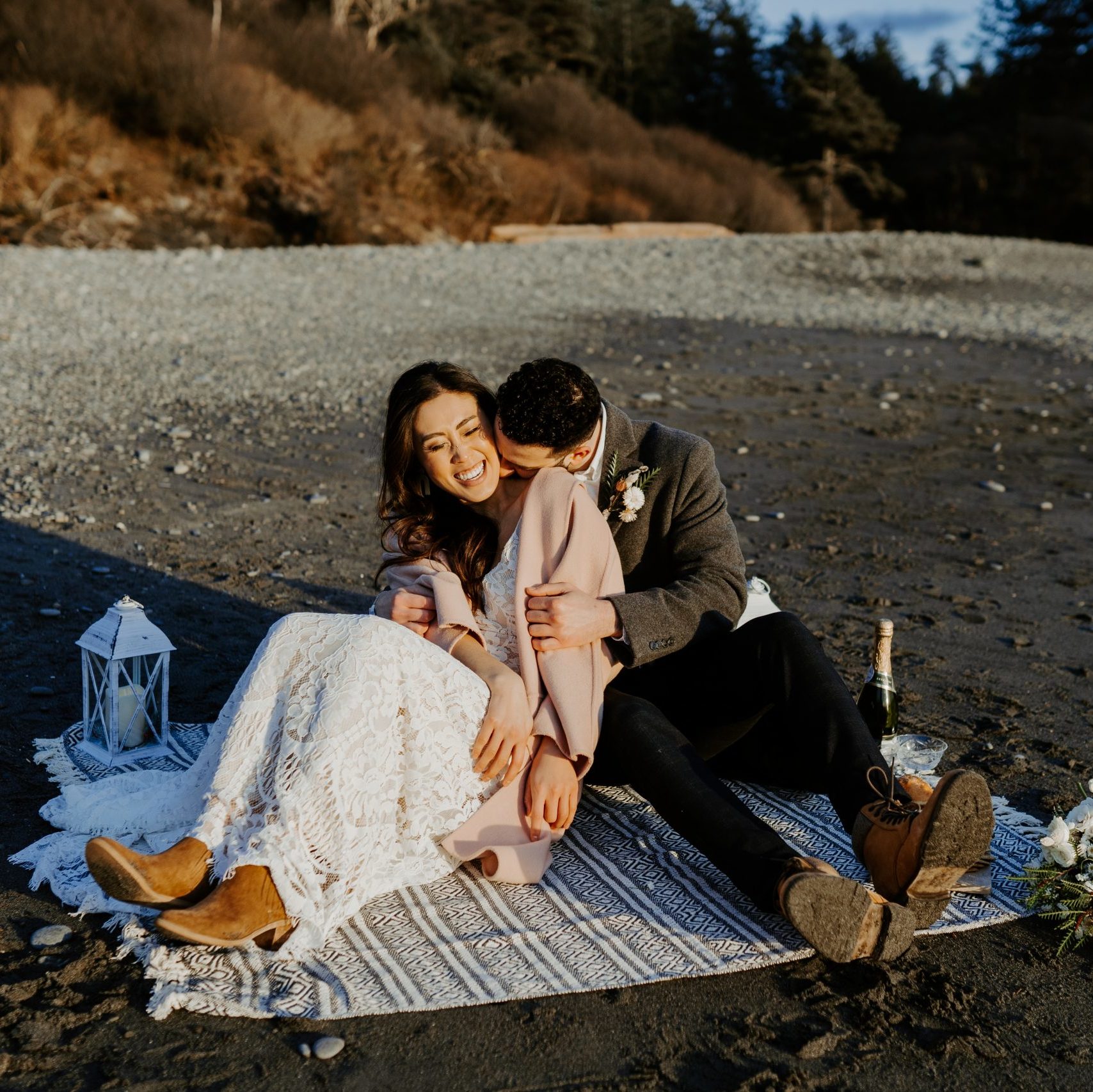 Eloping couple snuggling on a blanket at the beach