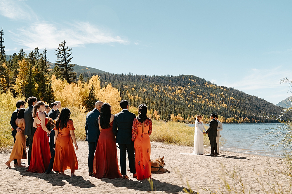 Small wedding ceremony by a lake in Colorado with fall colors all around. 