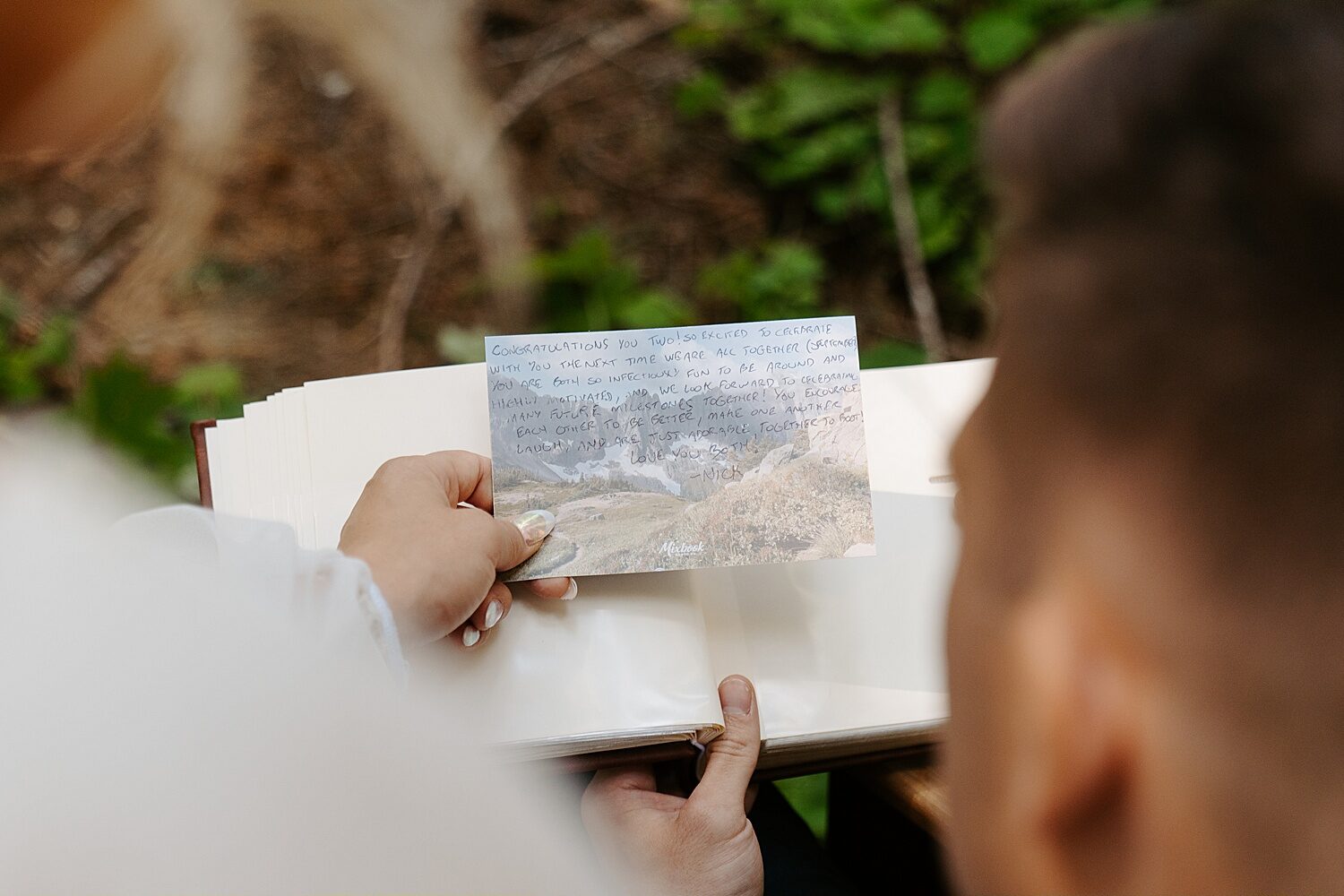Up close image of an album and a postcard with a heartfelt note to the bride and groom on their elopement day. 