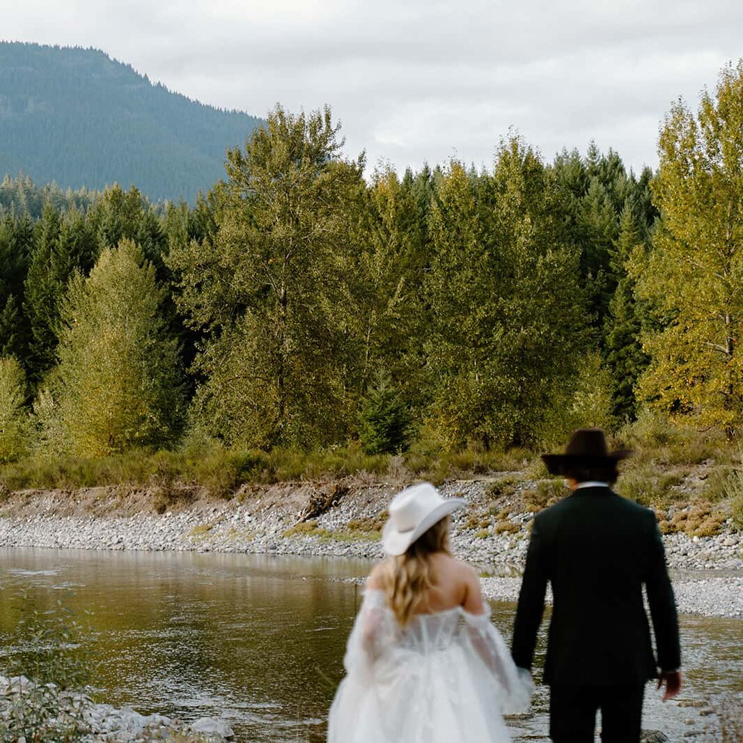 Blurry photo of a couple in wedding attire with a river, trees, and mountain clear in the background. 