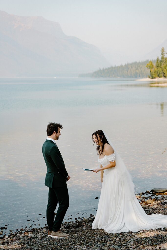 Bride saying wedding vows to groom at Lake McDonald in the summer. 