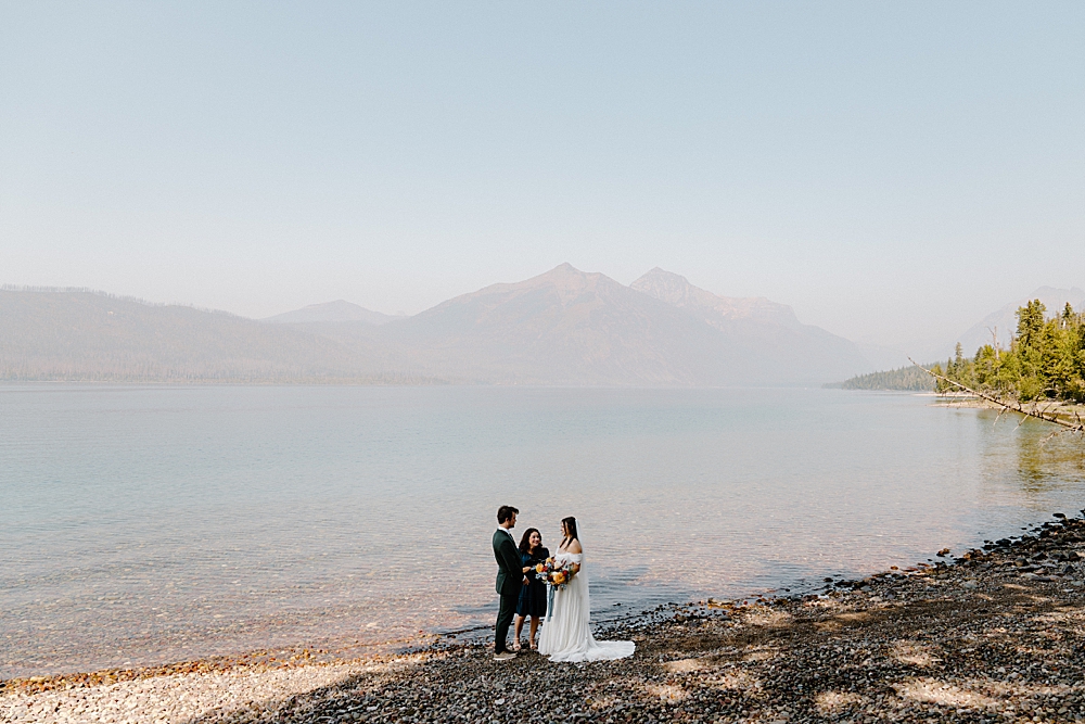 10-Mile Pullout elopement ceremony with an officiant, bride, and groom at Lake McDonald in Glacier National Park taken by Venture to Elope. 