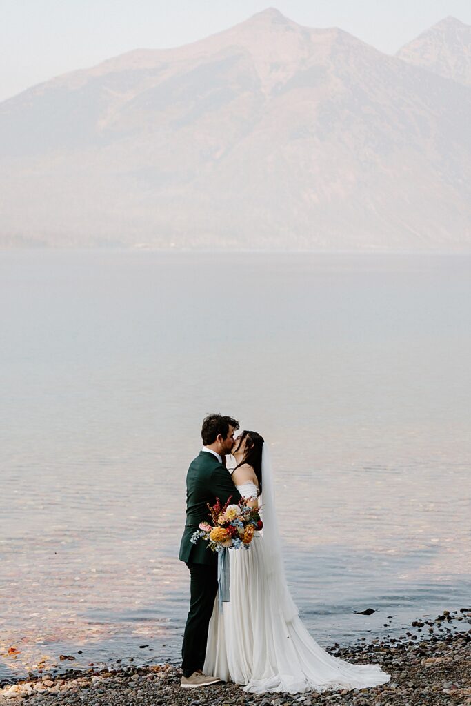 Bride and groom kissing at Lake McDonald after their elopement ceremony in Glacier. 