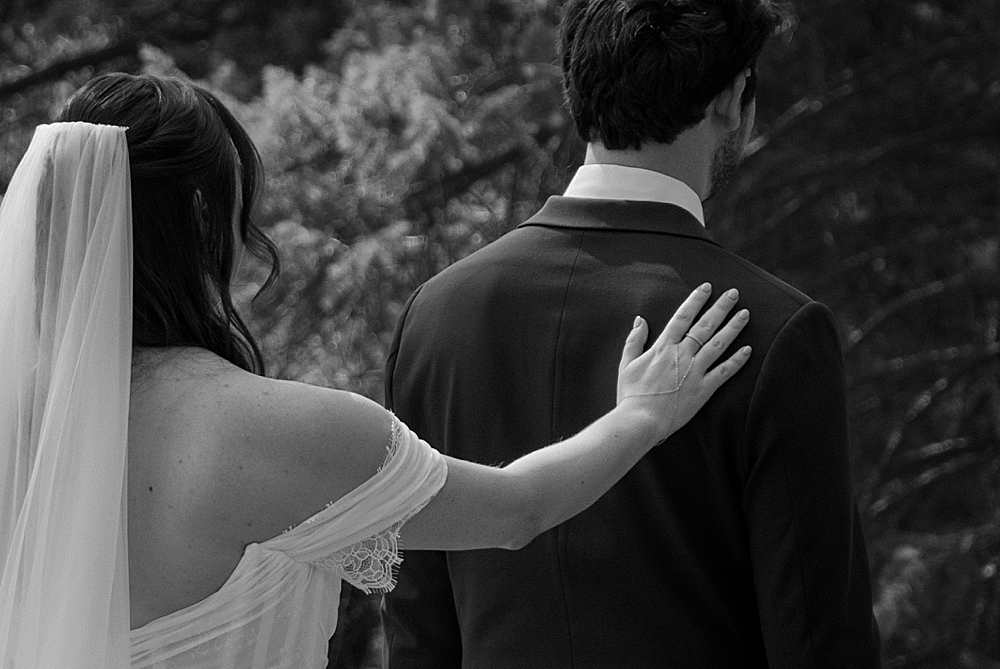 Black and white up-close image of the bride tapping the groom's shoulder for the "first look."