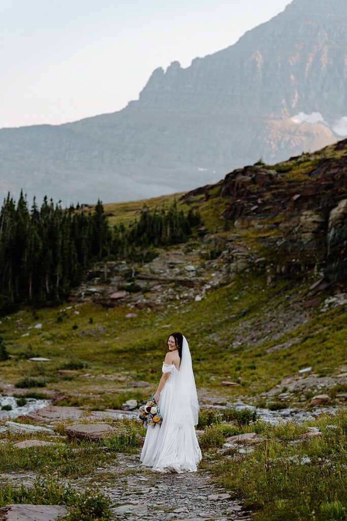 Glacier National Park bridal portrait with an off-the-shoulder dress, mid-length veil, and summer bridal bouquet. 