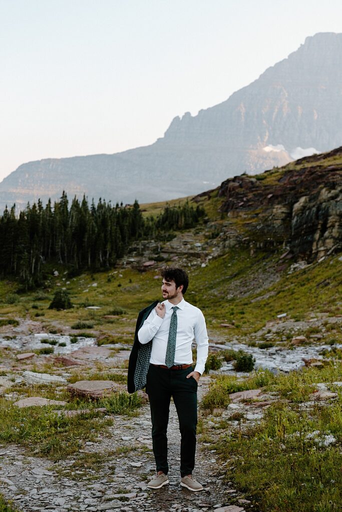Groom portrait in a green suit and floral green tie in Glacier Park. 