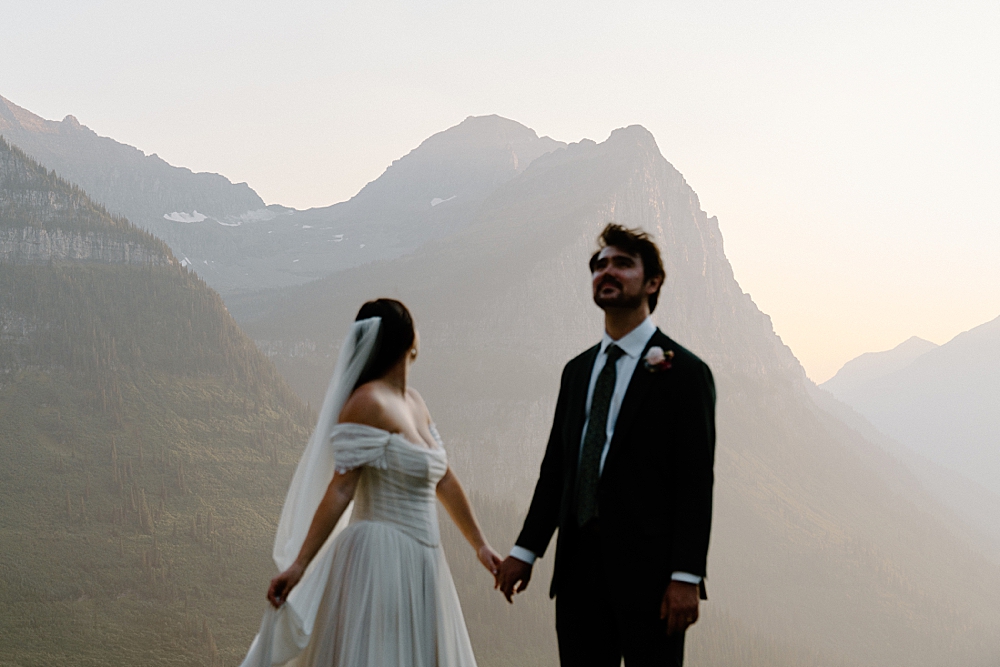 Blurry photo of bride and groom looking at the mountains at sunset in Glacier Park.