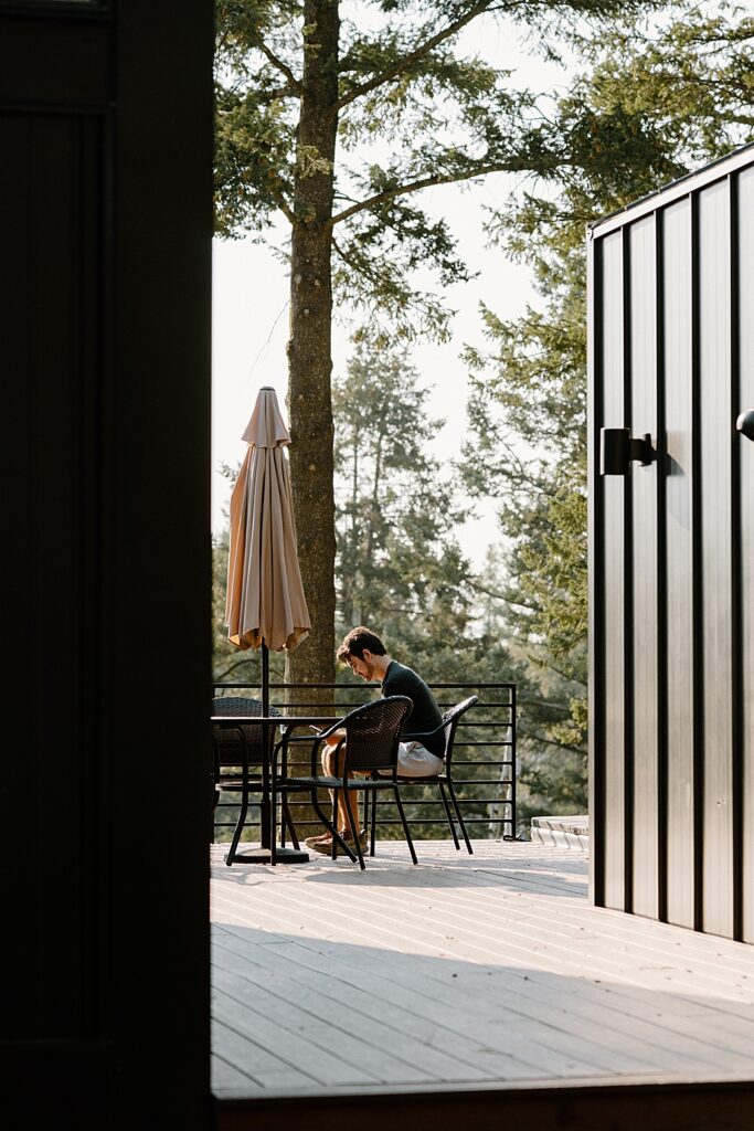 Man sitting at a chair reviewing his elopement vows outside an Airbnb in Montana.