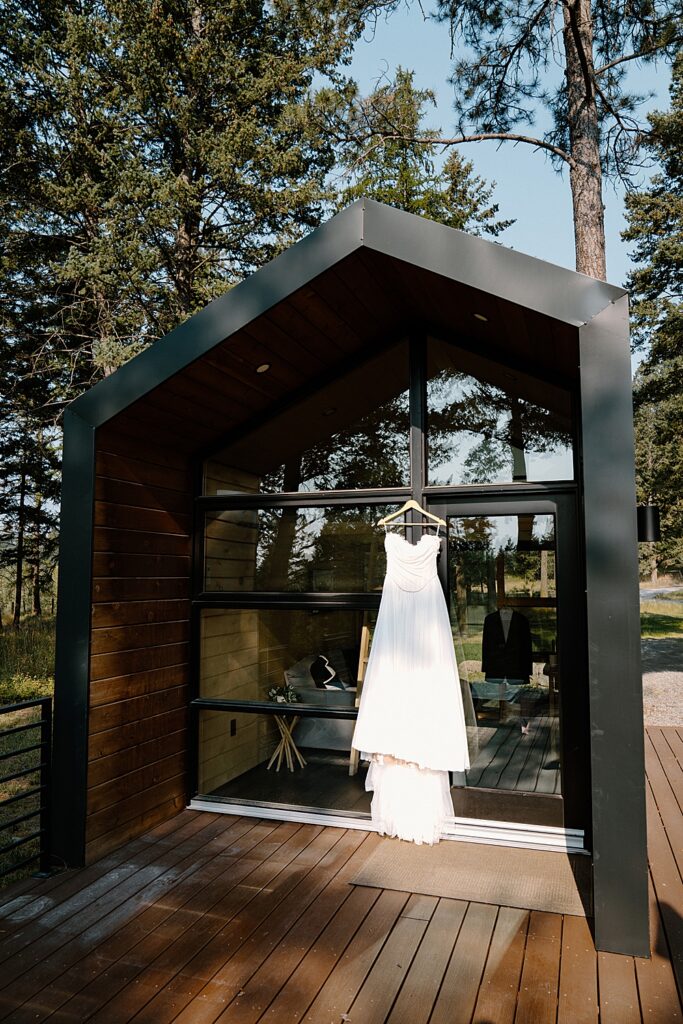 Off-the-shoulder wedding dress hanging from a tiny house in Flathead Valley, MT.
