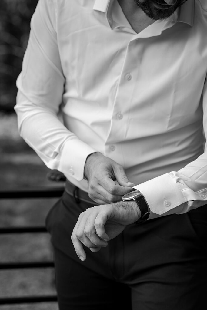 Black & white of groom putting on a watch