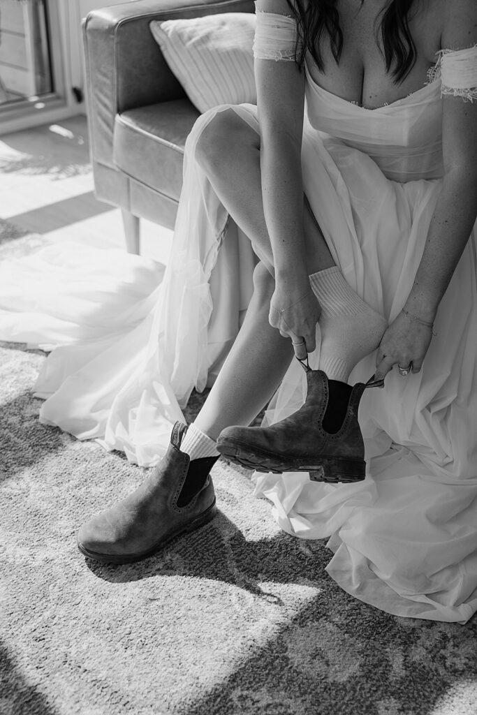 Black & white of adventurous elopement bride putting on her Blundstone's for her hiking wedding.