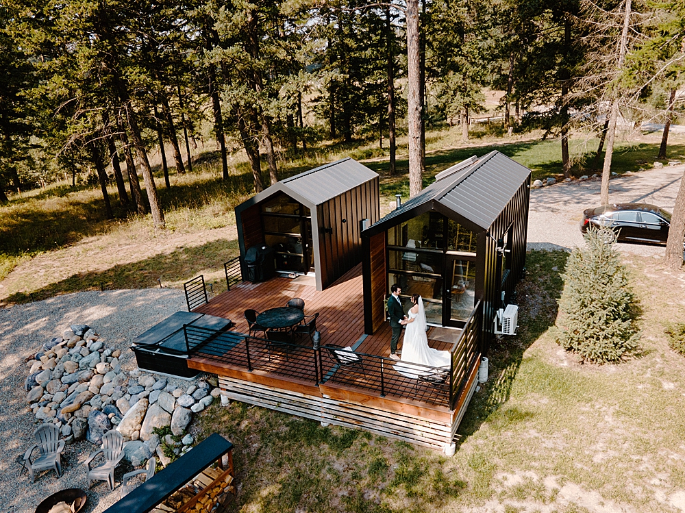 Tiny cabins in Montana with bride and groom standing on the deck
