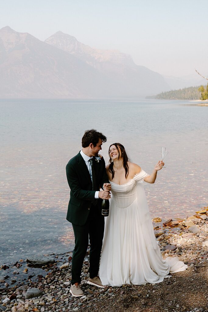 Bride and groom celebrating their elopement with champagne along Lake McDonald