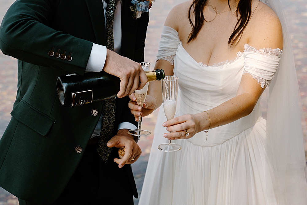 Bride and groom celebrating their elopement with champagne along Lake McDonald