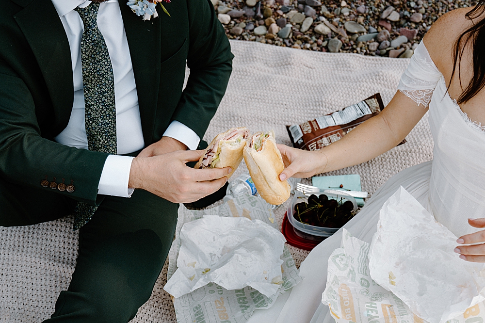 Bride and groom sharing Subway sandwiches after their intimate Lake McDonald elopement ceremony
