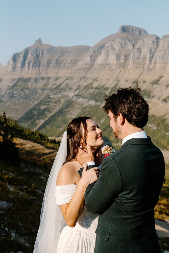 Groom holding bride's faec with the Rocky Mountains in the background
