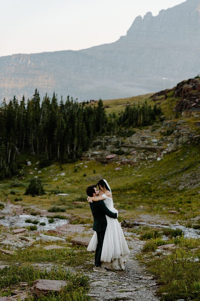 Groom holding bride on a trail in Glacier National Park