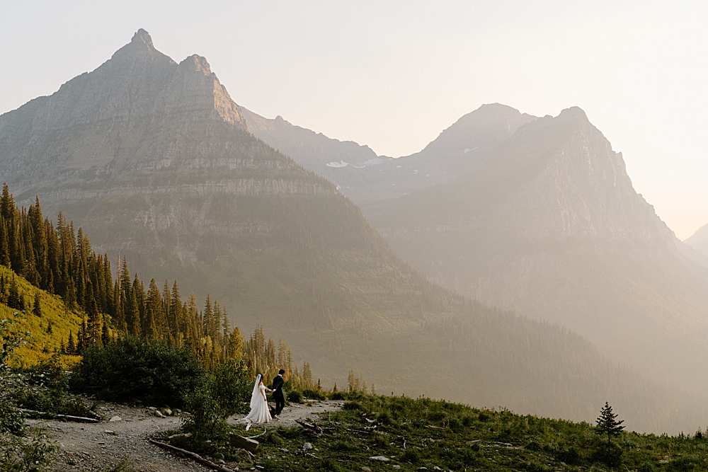 Groom leading bride down a dirt path at Big Bend in Glacier National Park