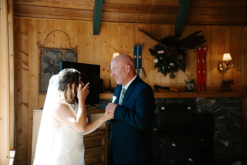 Bride and father of the bride sharing a moment after their first look in a cabin.