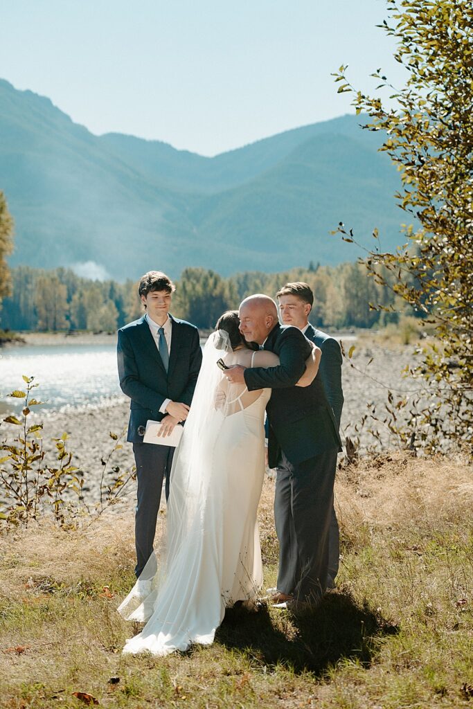 Father of the bride hugging the bride after walking down the aisle to the groom and officiant.