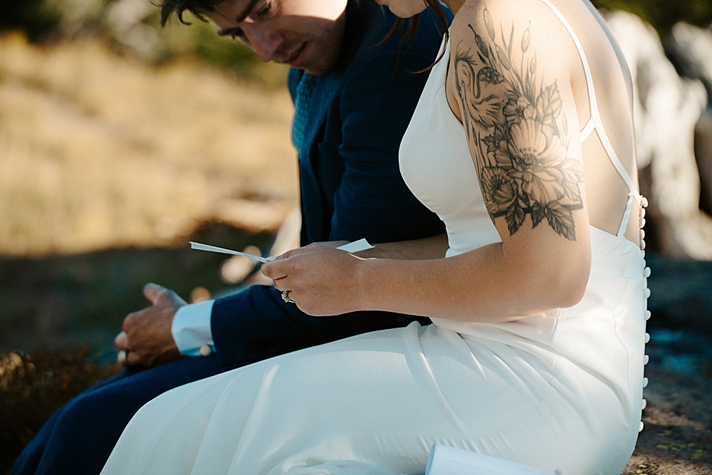 Up close of bride and groom sitting and reading a letter together on their elopement day at Mount Rainier.