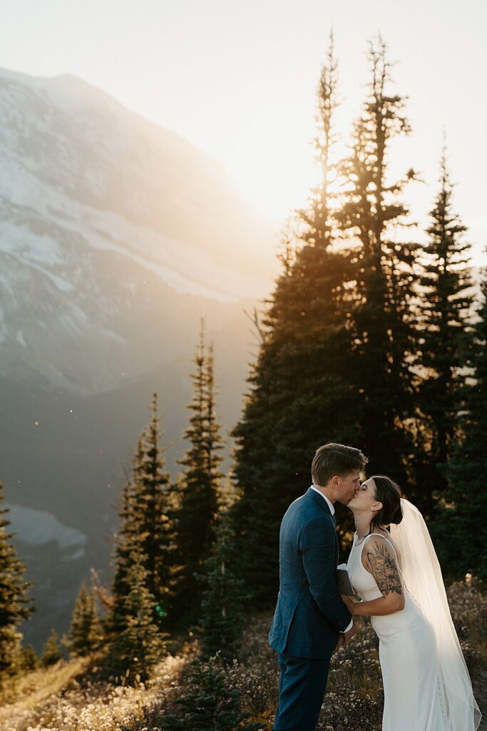Bride and groom kissing along a hiking trail at Sunrise, Mt Rainier during their sunset elopement.