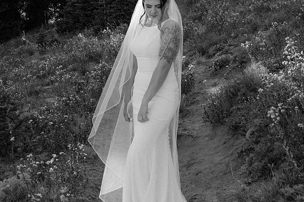 Black & white of bride looking down while her veil is loosely wrapped around her.